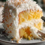Moist slice of pineapple coconut cake with creamy coconut frosting and pineapple filling on a grey plate