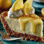 Slice of creamy no-bake lemonade pie with golden graham cracker crust and lemon wedge garnish on a teal dessert plate